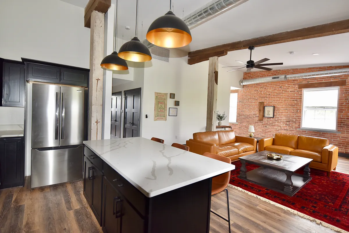 The living room features an open layout with optimal seating throughout, a desk/work space and a smart TV. The room features ceiling spotlights that are dimmable (its a whole mood) and a ceiling fan. - 101 W Broadway St #C