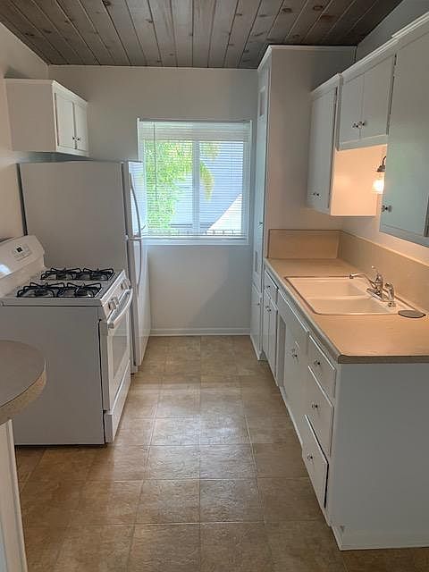 Galley kitchen with stove, refrigerator and garbage disposal.