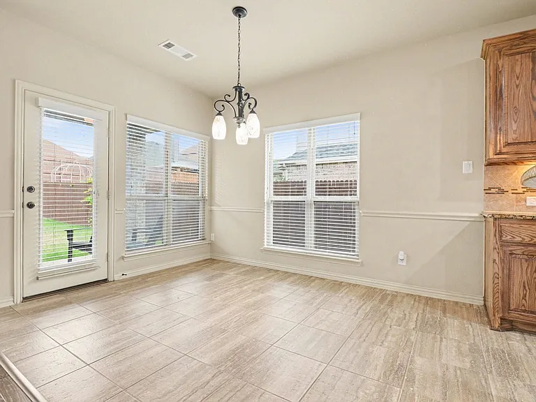 Dining area featuring light-toned tile flooring, a glass-paneled exterior door, and two large windows