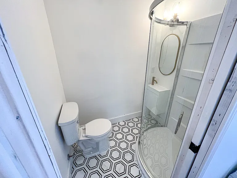 This bathroom has a walk in corner shower, marble tile, a small floating vanity, and pocket door for easy access!