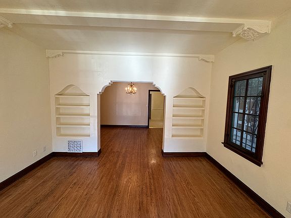 Living room with built-in bookshelves, decorative beams and wood floors.