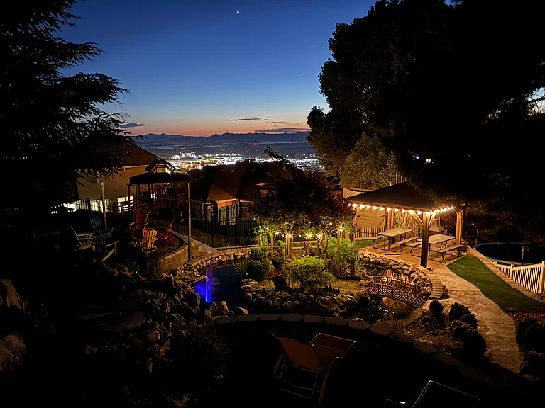 Night time snapshot of oasis backyard with island in middle of pond.