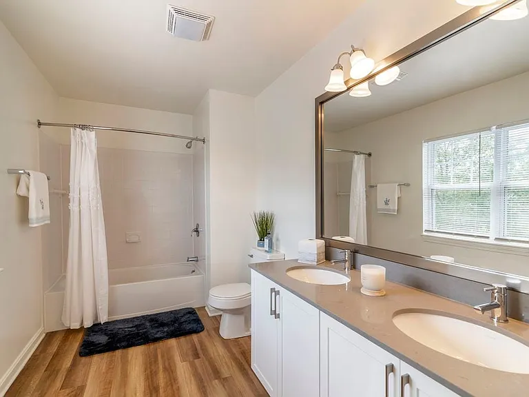 Renovated Package I bath with white cabinetry, grey quartz countertops, and hard surface plank flooring