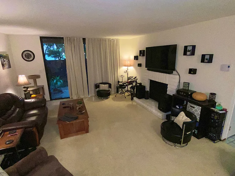 Living Room, with a view out to private patio, wood-burning fireplace and built-in air conditioner.