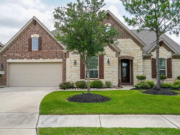 Beautiful curb appeal with stone front elevation and lush landscaping.