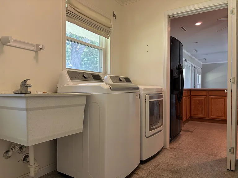 Spacious laundry room featuring abundant built-in storage, utility sink, washer and dryer, and convenient exterior access.