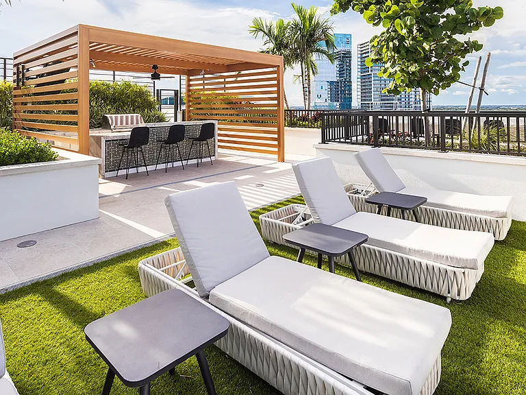 Griffis West Palm apartments rooftop deck with BBQ grill, gazebo, turf lawn, and lounge chairs.