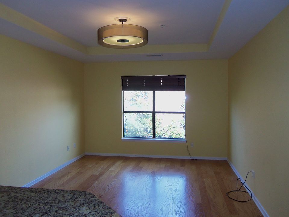 The spacious living room features hardwoods, a tray ceiling & custom lighting.