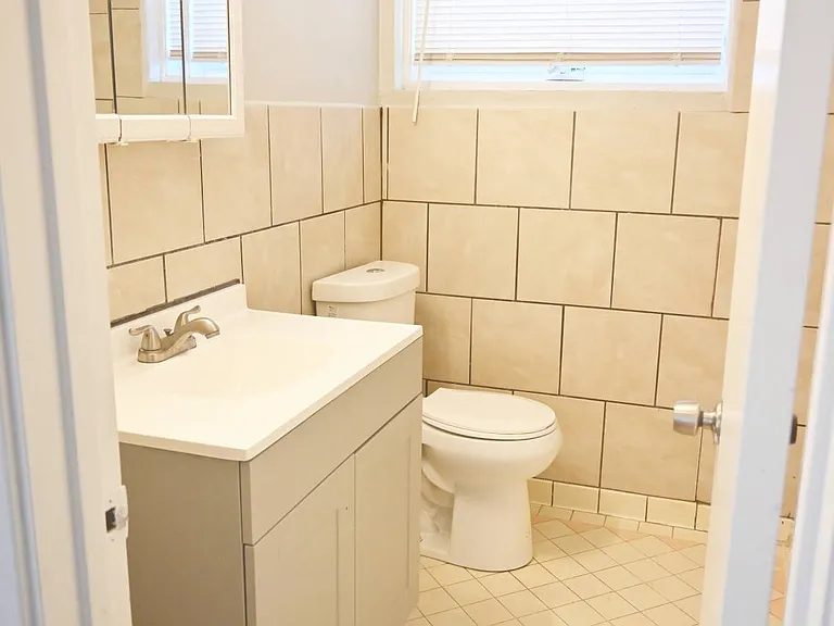 Bathroom with white tiles at Benson Crest Apartments.