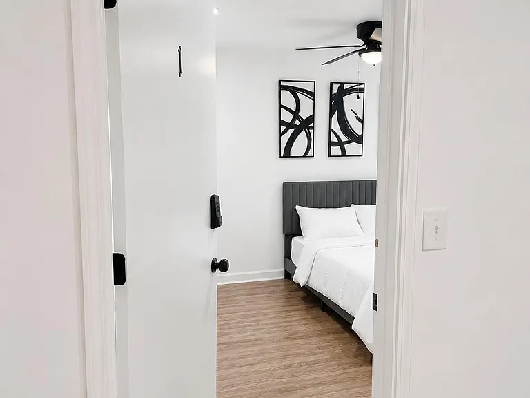 Private bedroom with wood-look flooring, upholstered bed, and ceiling fan, plus a secure entry for added peace of mind.