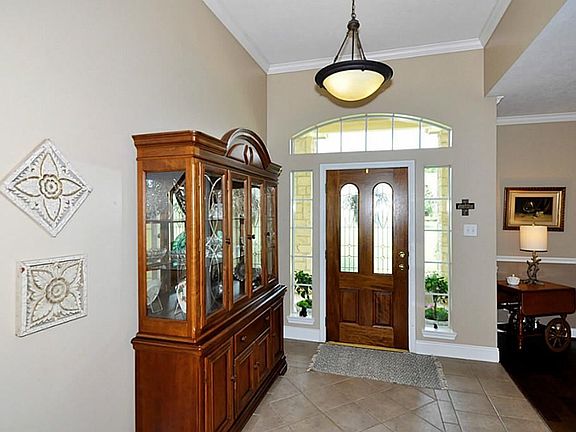 THE ENTRY FOYER AREA VERY HIGH CEILINGS, TRANSOME WINDOW ABOVE THE DOOR AND A STONE LIKE TILE INVITES YOU IN.