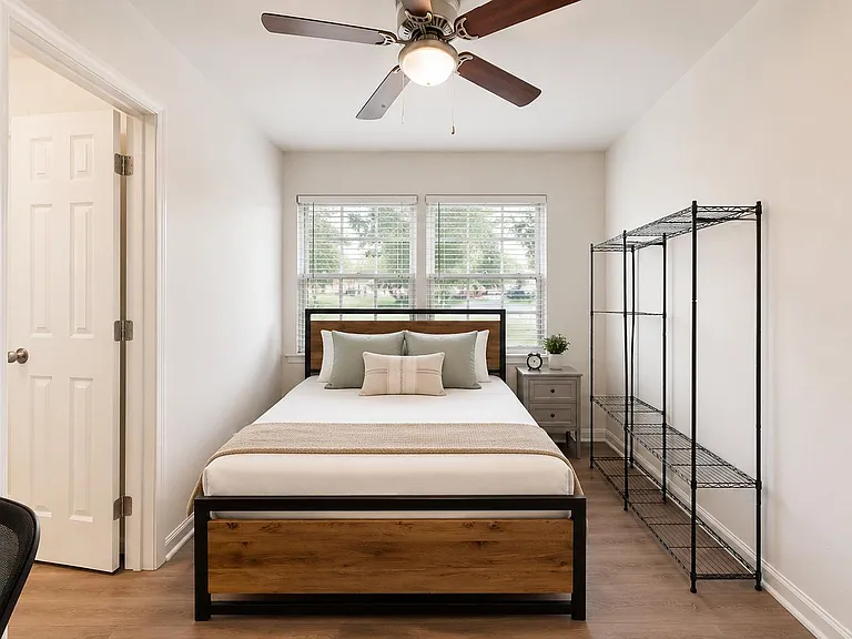 Well-appointed bedroom with a full bed, ceiling fan, dual windows, nightstand, and open shelving for extra storage.