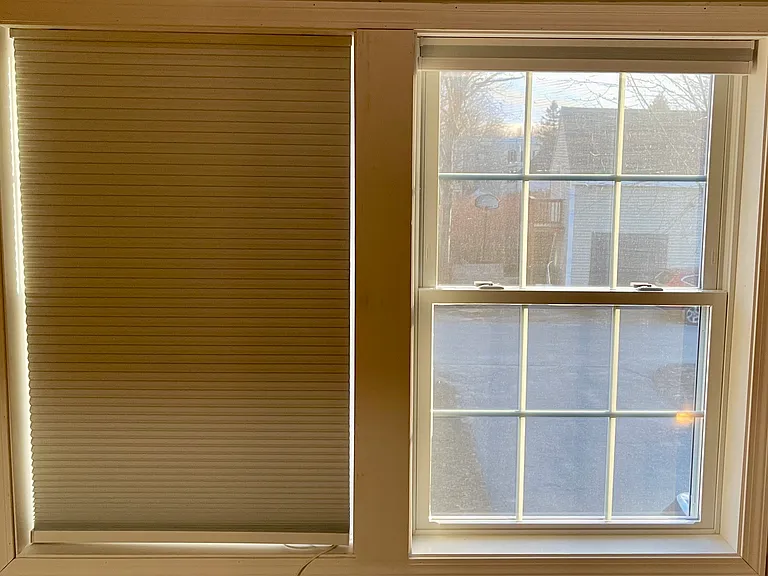 Blackout shades pulled down over one of two windows