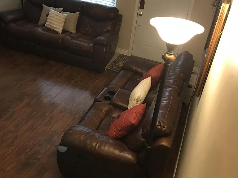 Living room has leather reclining couch and love seat.