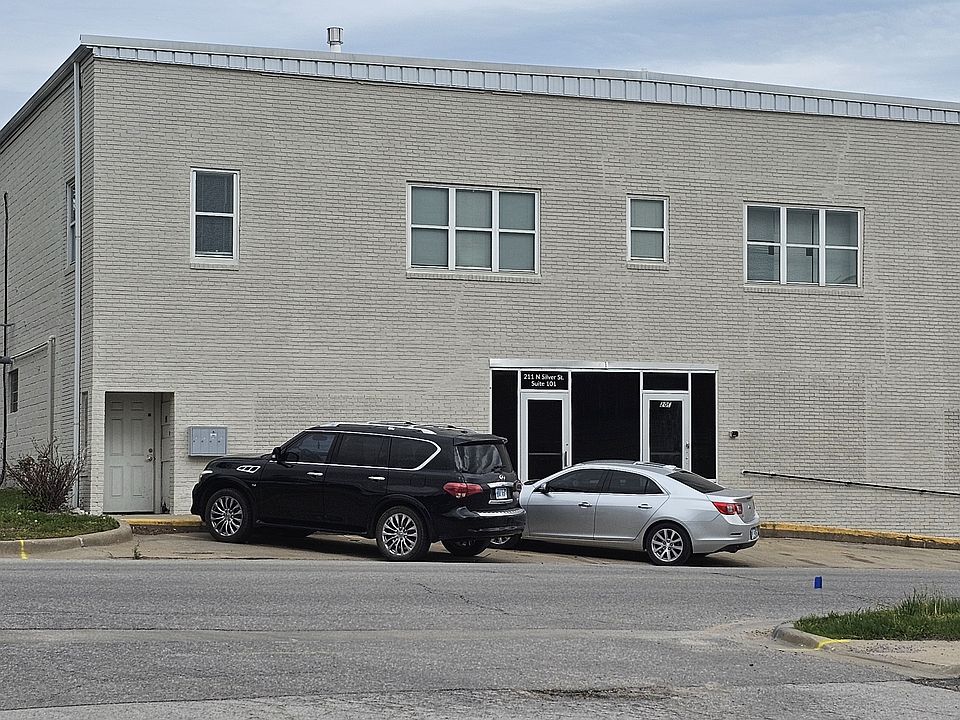Entrance to apartments through the far left door. Parking in front of the building as well as a large lot on other side.