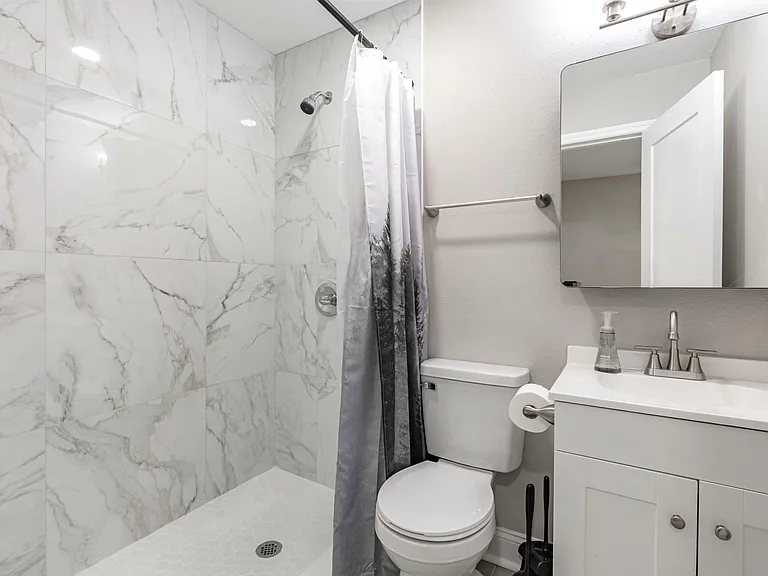 Updated bathroom with a tiled walk-in shower, vanity with storage, and a large mirror for everyday convenience.