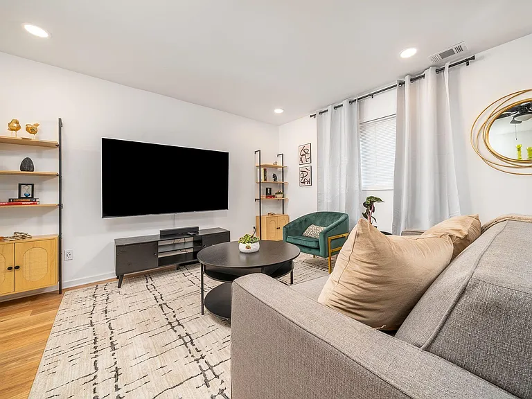 Inviting living room with a large wall-mounted TV, ample seating, and open shelving for books and decor.