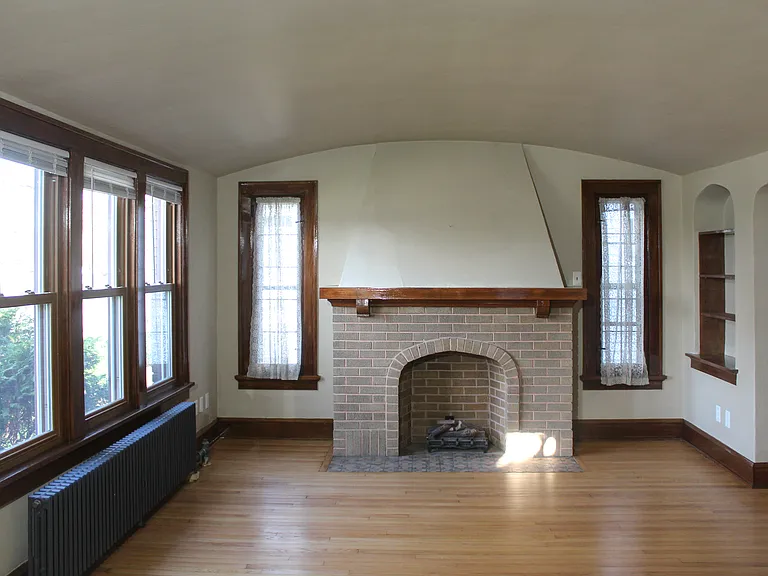 Living room with electric fireplace, original refinished woodwork, and wood floors.