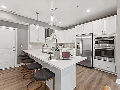 The gourmet kitchen features an electric cooktop, double wall ovens, refrigerator, vented hood, expansive countertops and deep soft-close cabinetry. The island comfortably seats five and is the perfect space for cooking, dining, and entertaining.