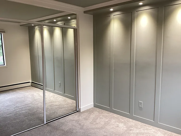 Bedroom with lighted accent wall and glass mirror closet