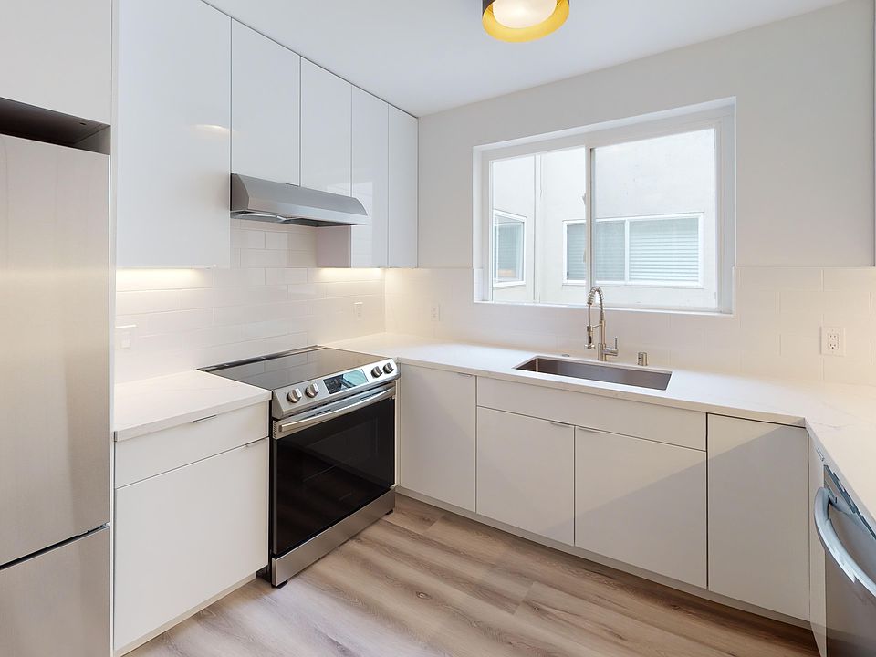 Kitchen with cabinets, refrigerator, stove, range hood, and sink