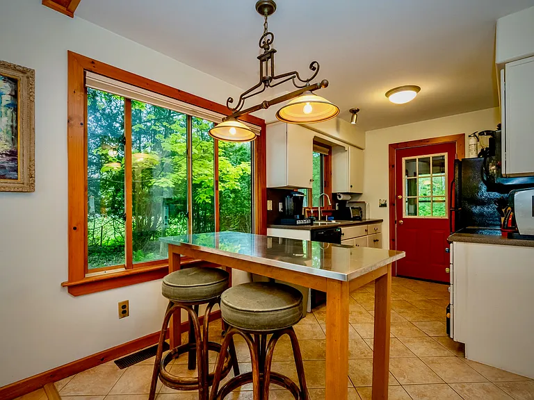 Warm, welcoming kitchen with natural light, wood accents, and a charming breakfast nook overlooking the outdoors.