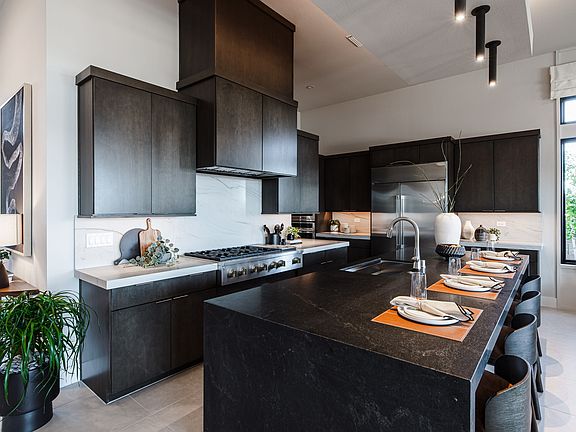 A modern, sleek kitchen with dark cabinets, a large countertop, and various kitchen appliances and d