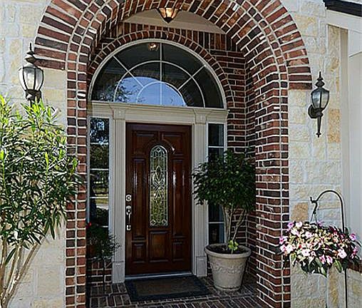 The arched entry is trimmed with brick