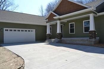 The driveway is cement and leads up to the front entrance and the garage area. The attached garage i