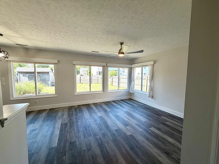 Large living and dining area with huge windows, overlooking fanced back yard, High end ceiling fan, flat screen tv mount and solid surface flooring.