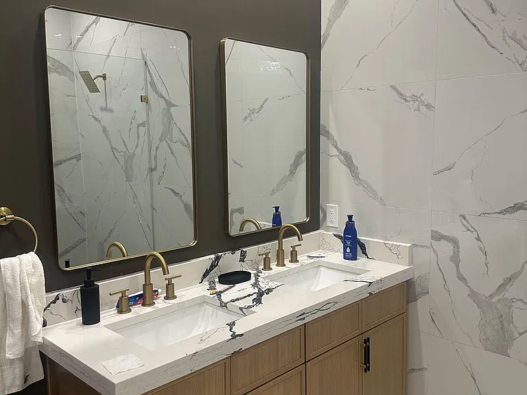Stylish double-vanity bath with marble-look tile, roomy counter space, and ample storage for shared routines.