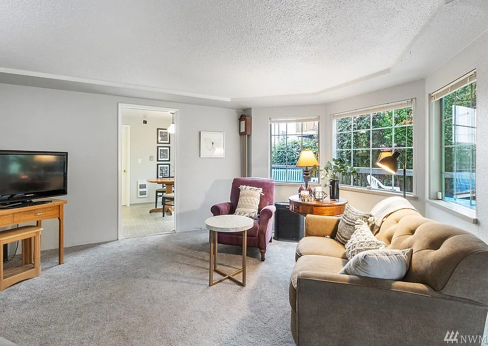 A view of the Living Room with large windows. Light and bright. Doorway leads to kitchen.