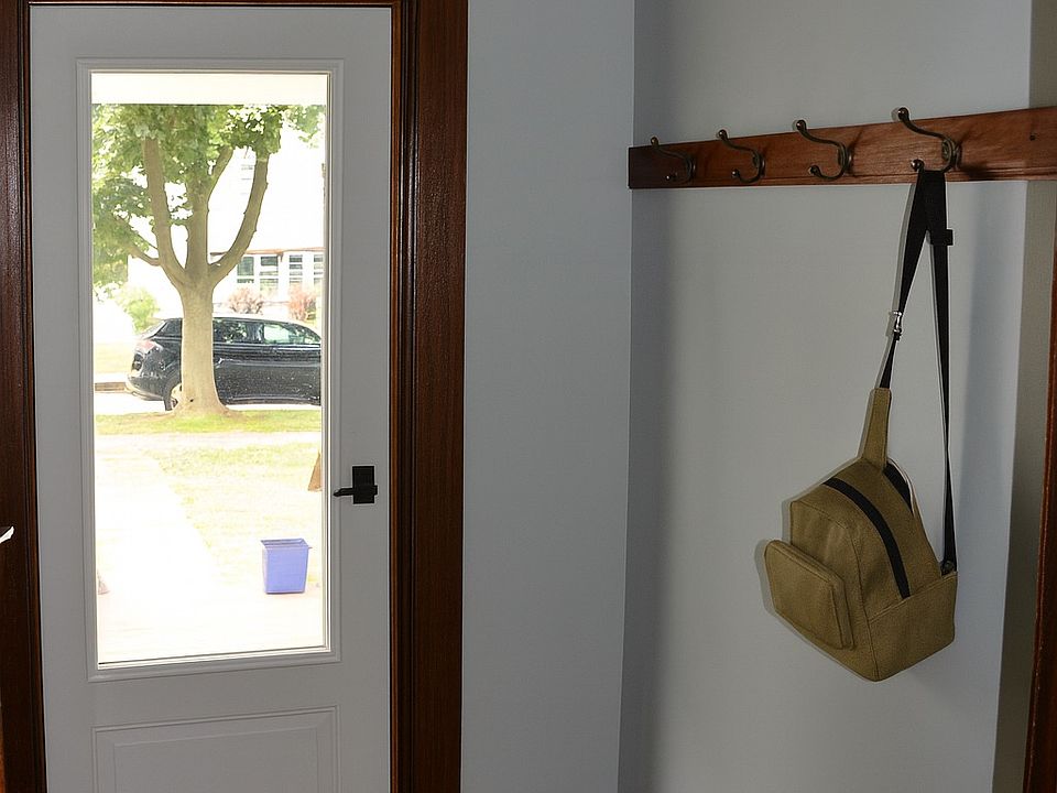 Welcoming foyer with natural light from a glass-paneled front door. Features coat hooks for storage and rich wood trim that adds timeless character.