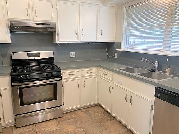 Kitchen has a view of the front yard. Stainless steel dishwasher and stainless steel sink.