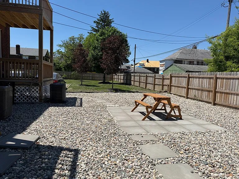 The yard behind the building w picnica area. Note that past the cobblestones, there is ample, fenced-in, grassy yard space and trees.
