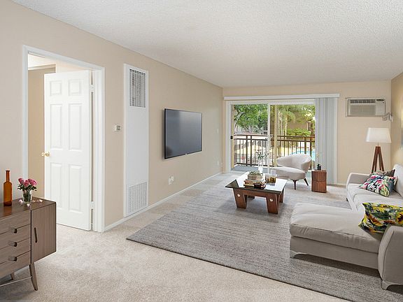 Carpeted and staged living room with sliding door leading to balcony.