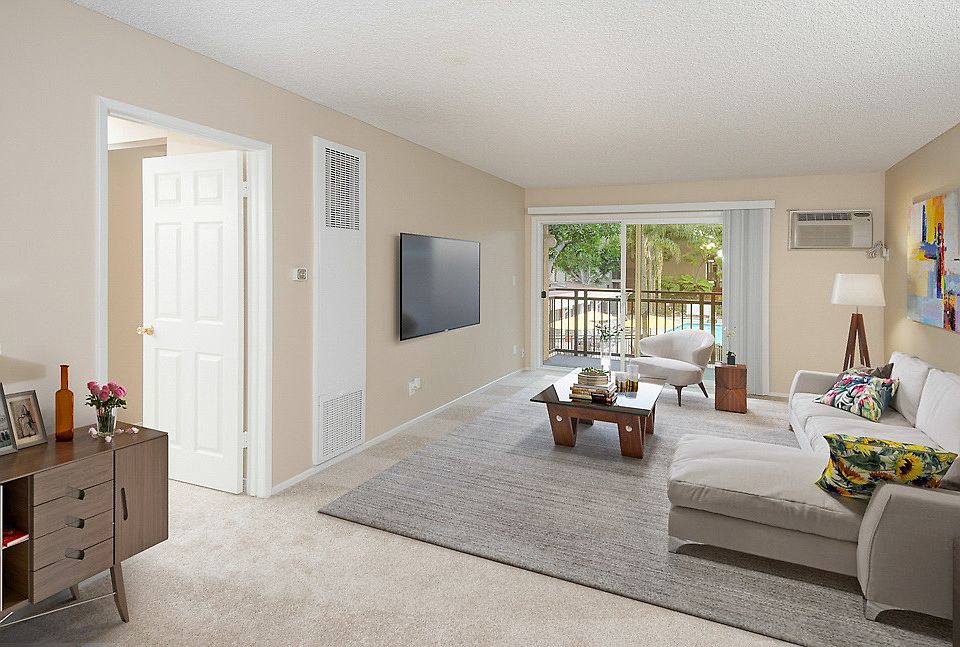 Carpeted and staged living room with sliding door leading to balcony.