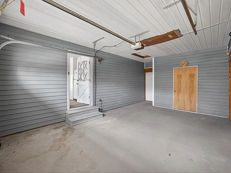 Garage and spacious storage area behind wooden door.
