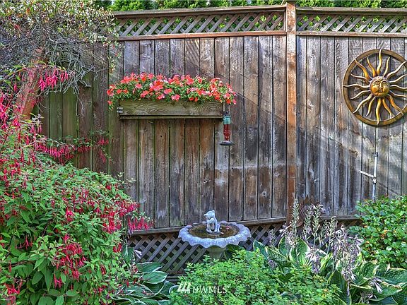 The living room looks out onto the flower garden that's filled with dappled light.  Plants are protected from the scorching sun, providing a soothing oasis awaiting your gaze.