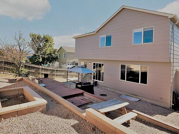 Tiered back yard features fire pit, planters, deck and picnic table.