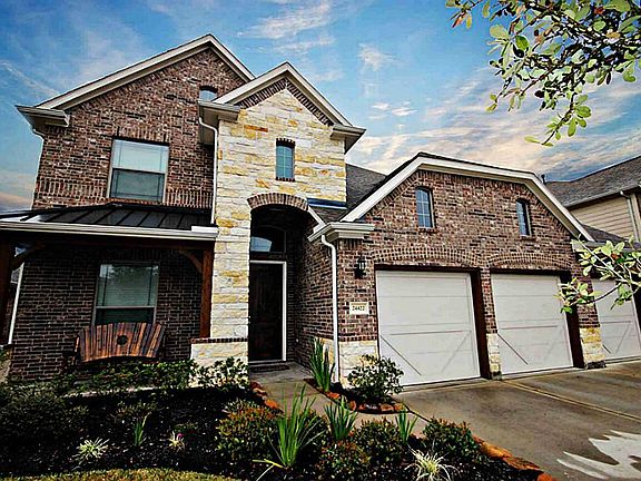 Gorgeous stone, brick, and wood elevation with landscaped flowerbeds and pretty front porch.