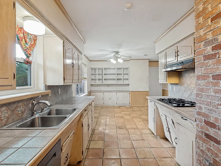 This French inspired kitchen is equipped with a gas stove top and vent hood, 2yo stainless steel French door refrigerator, dishwasher and microwave, double ovens, and so much character with the exposed brick and tiled flooring.