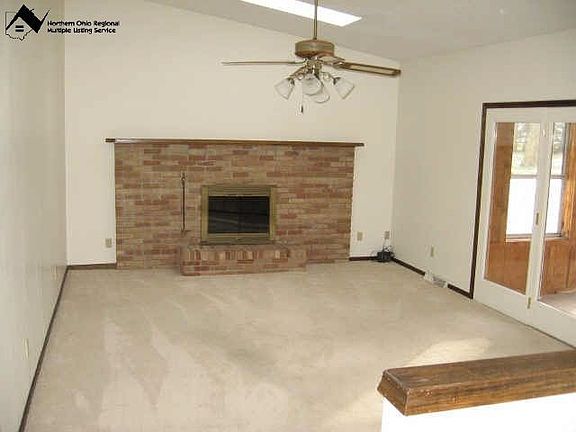 Living room with vaulted ceilings, skylights, and a woodburning fireplace.