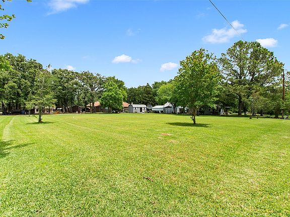 Expansive side yard showcasing two additional vacant lots adjoining the home, offering abundant green grass and endless possibilities for outdoor living, future expansion, or added privacy.