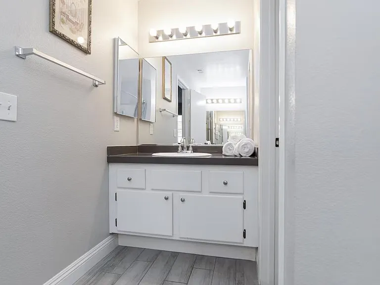 Bathroom vanity area with wide mirror, ample under-sink storage, and updated tile flooring for easy upkeep.