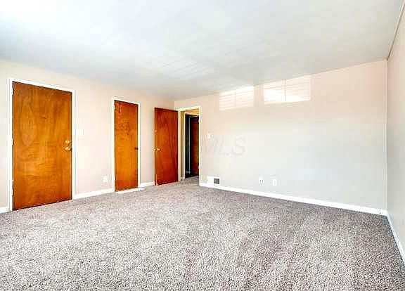 Large living room with new carpet. Closet space leads to the hallway for the kitchen, bedroom, and full bath with bathtub.