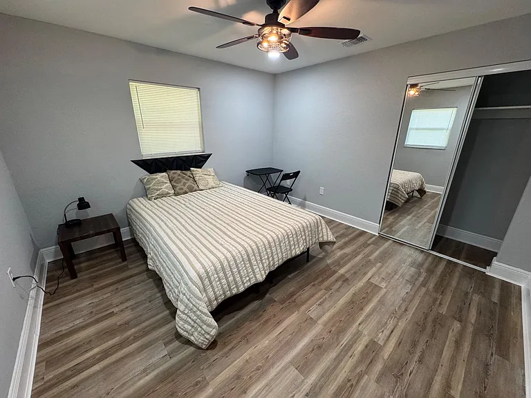 Bedroom with a full bed, ceiling fan, waterproof floors, and sliding mirrored closet doors for convenient storage.