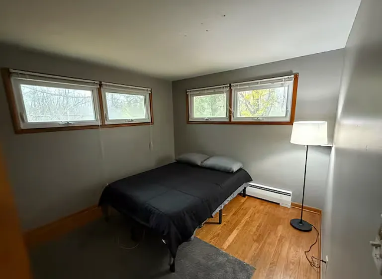 Comfortable second bedroom with hardwood floors and elevated windows for added privacy.
