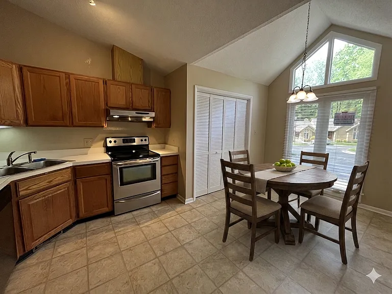 Kitchen with vaulted ceiling and dining area. Oak cabinetry and newer stainless steel appliances. Easy to access full size laundry closet.