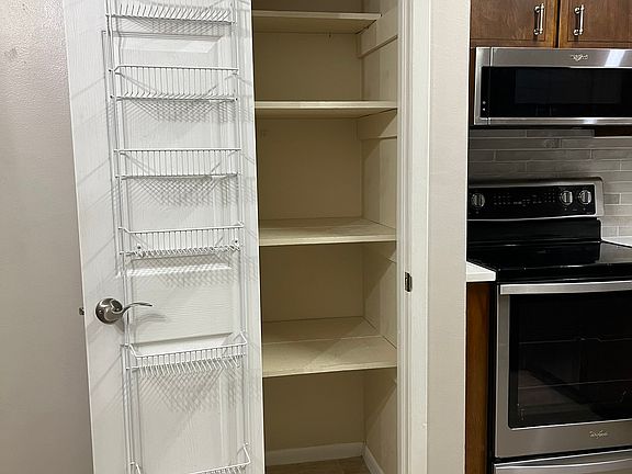 This is a view of the pantry. You can also see the 5 burner glass top stove and convection oven and the over the stove slim microwave/vent.